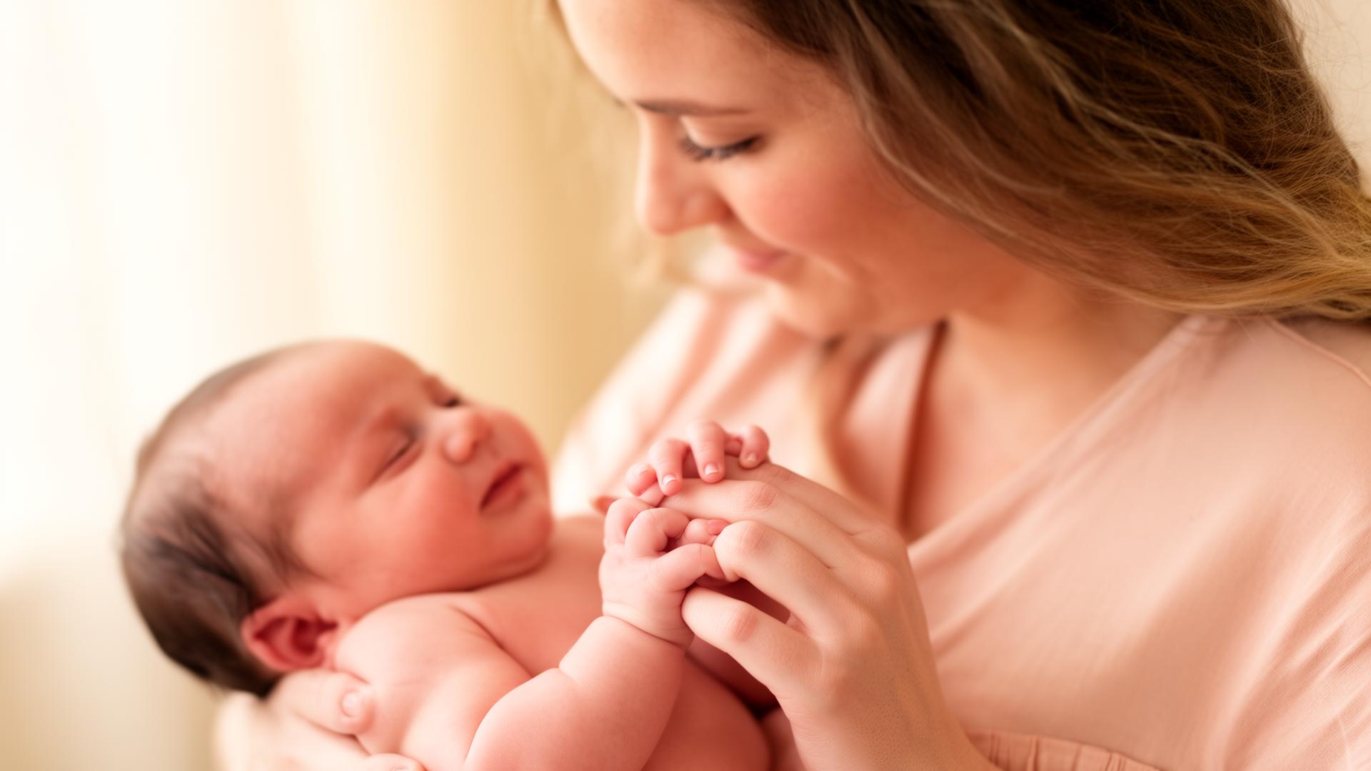 Mãe segurando carinhosamente a mão do bebê recém-nascido